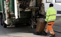 Müllmann fährt Mülltonne an Müllabfuhrfahrzeug