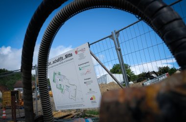Blick auf die Baustelle im Schillerareal durch den Bauzaun mit Bauschild