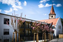 Gebäude des betreuten Wohnen mit blühenden Kirschbäumen im Vordergrund