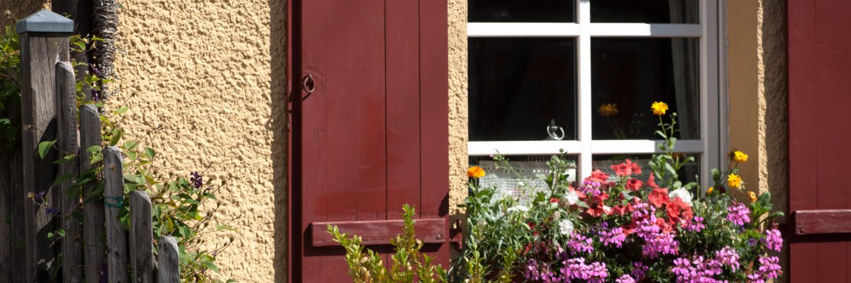 Blick auf ein Fenster mit bunten Blumen in einem Blumenkasten Blick auf ein Fenster mit bunten Blumen in einem Blumenkasten