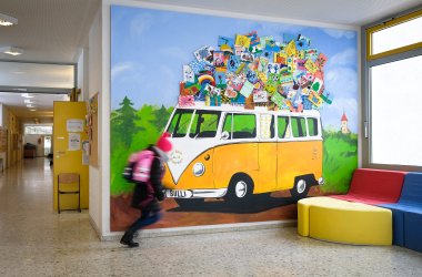 Ein Kind rennt vor einem Wandbild eines Bullis in der Grundschule Simmozheim