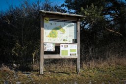 Hinweistafel zum Naturschutzgebiet "Hörnle und Geißberg", das vor einer Hecke steht