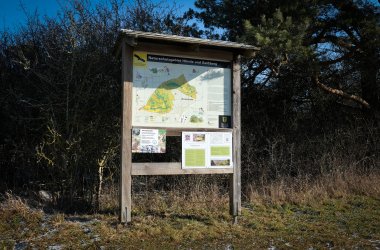 Hinweistafel zum Naturschutzgebiet "Hörnle und Geißberg", das vor einer Hecke steht